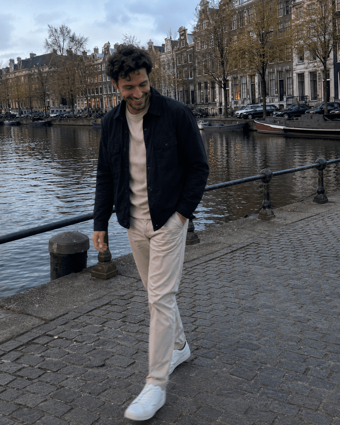 Full body photo of a man walking along an Amsterdam canal