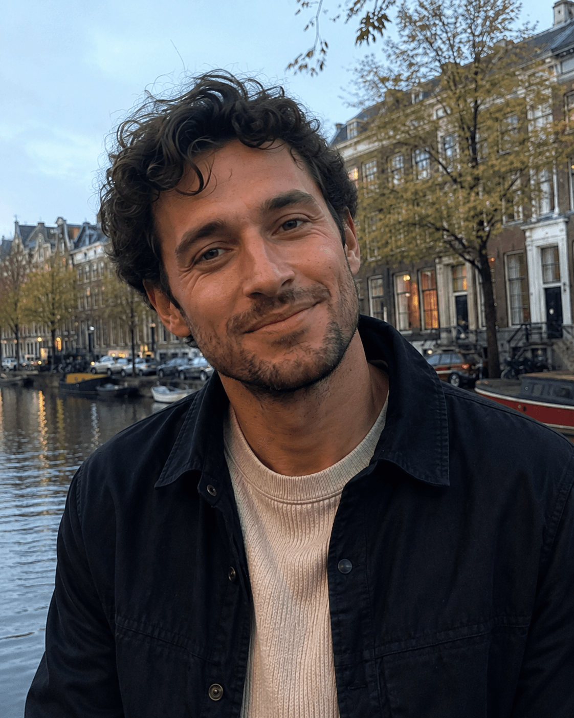 Close-up portrait of a smiling man on an Amsterdam canal at dusk